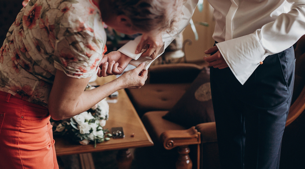 mother helping son with cuff links for his wedding day