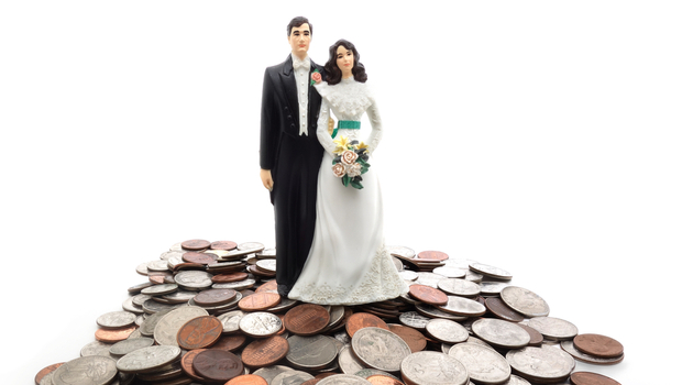 plastic bride and groom standing on mountain of money coin
