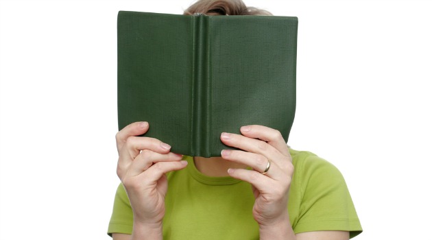 woman hiding behind book