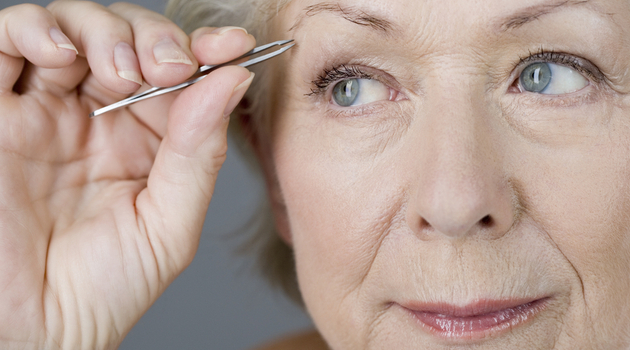 mature woman tweezing eyebrows