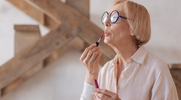 senior woman applying lipstick